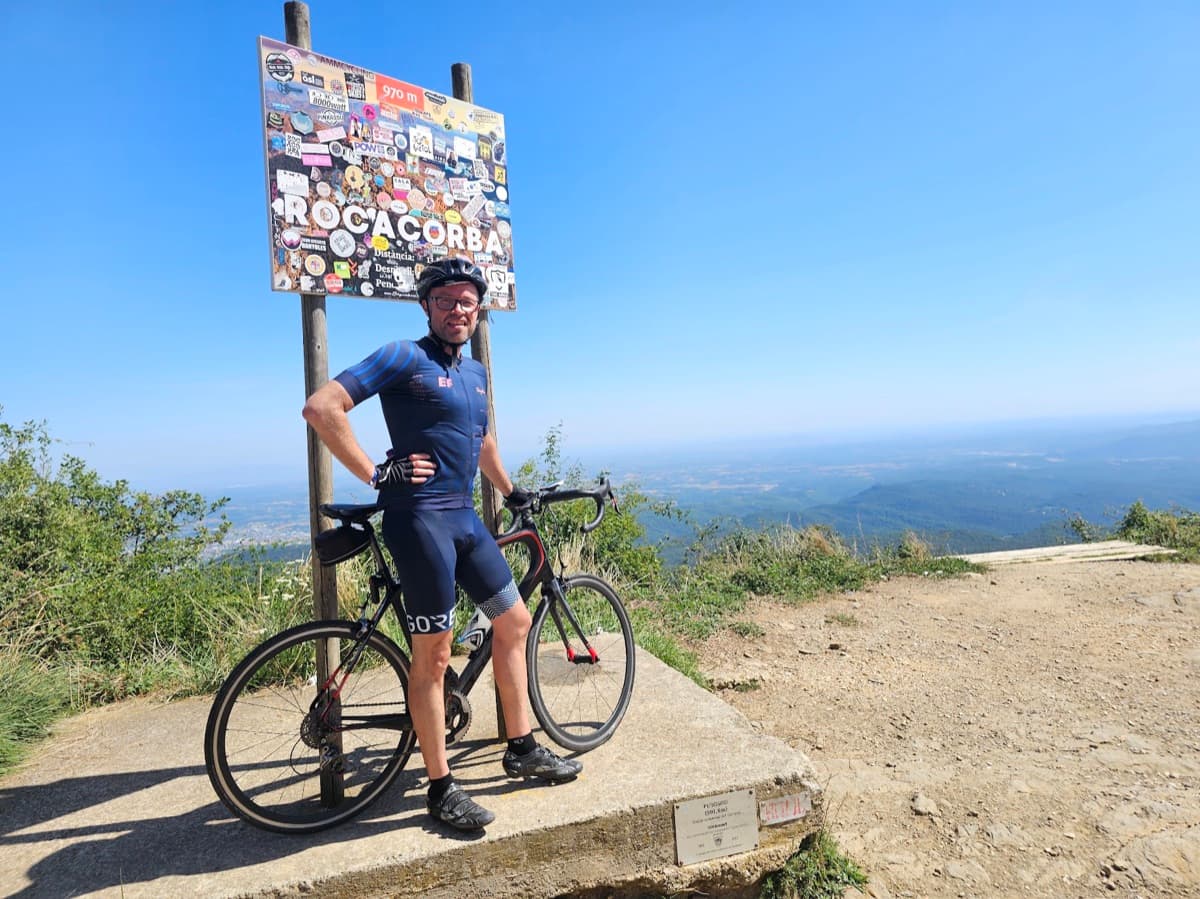 Gabriel with his road bike at the Rocacorba summit sign in Catalonia
